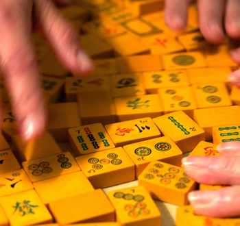 closeup of hands and mah jongg tiles